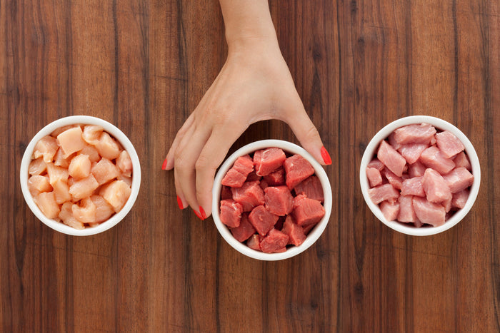 Hand selecting one dish of raw meat amongst 3 different dishes