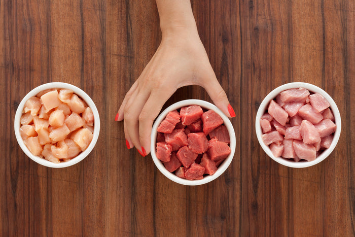 Hand selecting one dish of raw meat amongst 3 different dishes